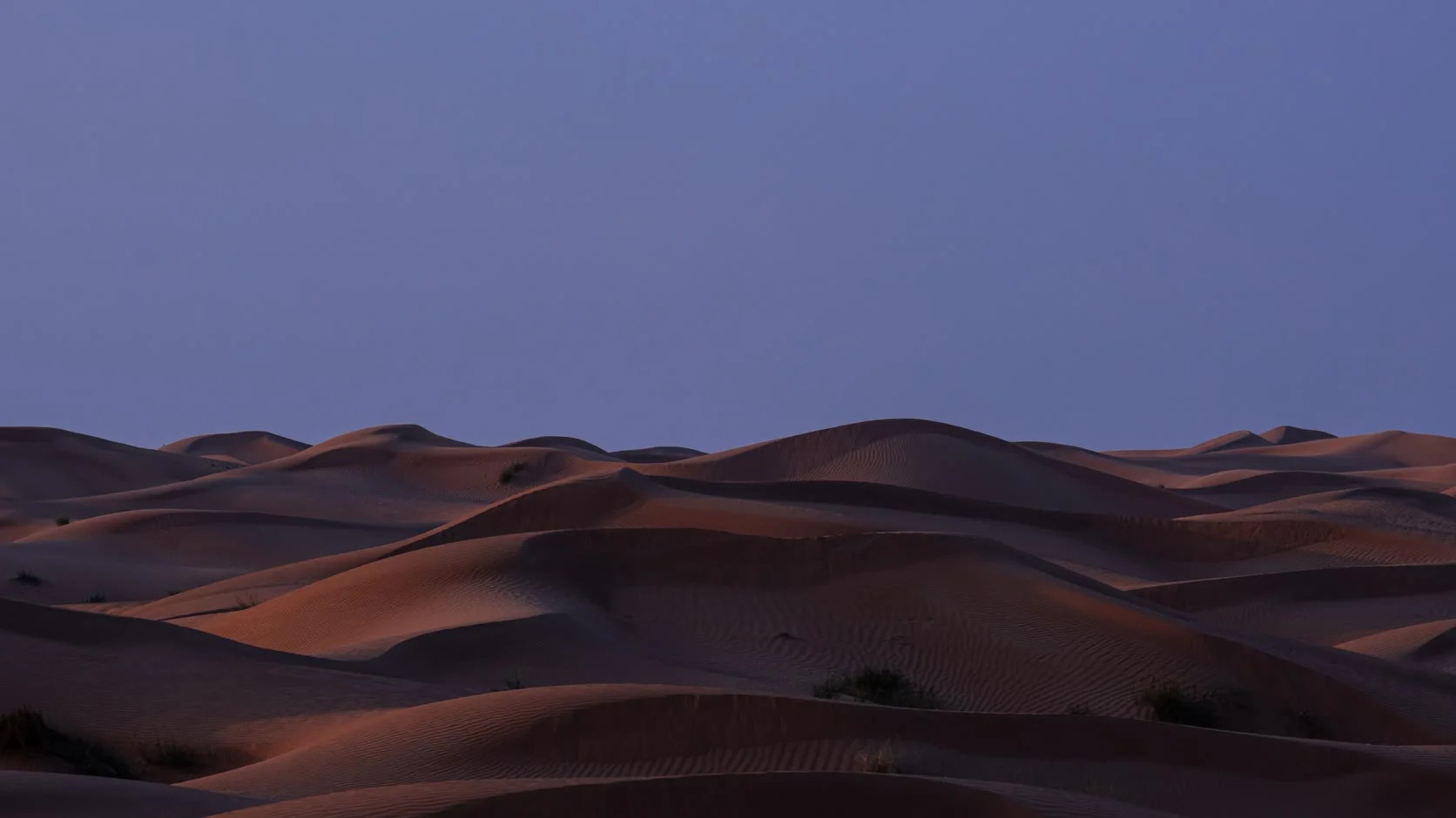Sand dunes at dusk under a violet sky